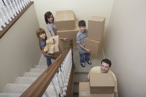 Movers carrying furniture down stairs in Merton